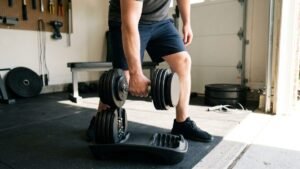 Adjustable dumbbell being lifted from its cradle base in a garage home gym