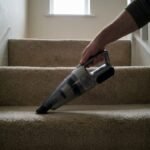 Handheld vacuum being used on carpeted stairs