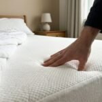 Hand pressing into a supportive mattress in a quiet bedroom