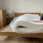Mattress in a box being unrolled onto a timber bed frame