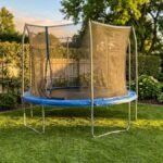 Round backyard trampoline with a safety net on green lawn