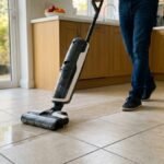 Cordless vacuum mop being pushed across a tiled kitchen floor