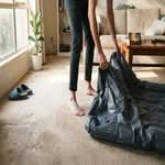 A person setting up the best air mattress in Australia on a carpeted floor, with natural light.