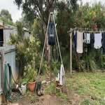A person holding the best camping shower Australia in a backyard setting.