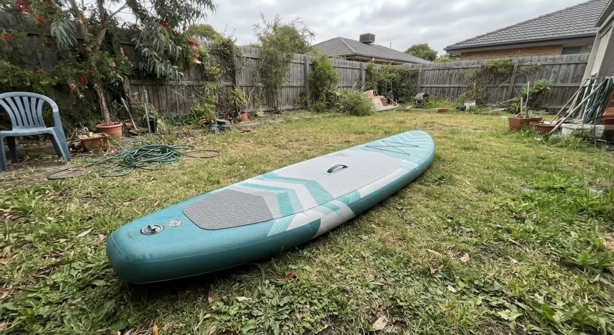A person's hand holding a deflated inflatable paddle board, ready for use in Australia. Focus on the 'best inflatable paddle board australia' aspect.