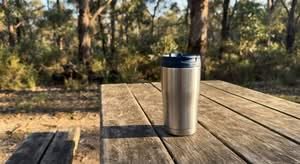 A top-rated travel coffee mug for use in Australia, pictured on an outdoor table.