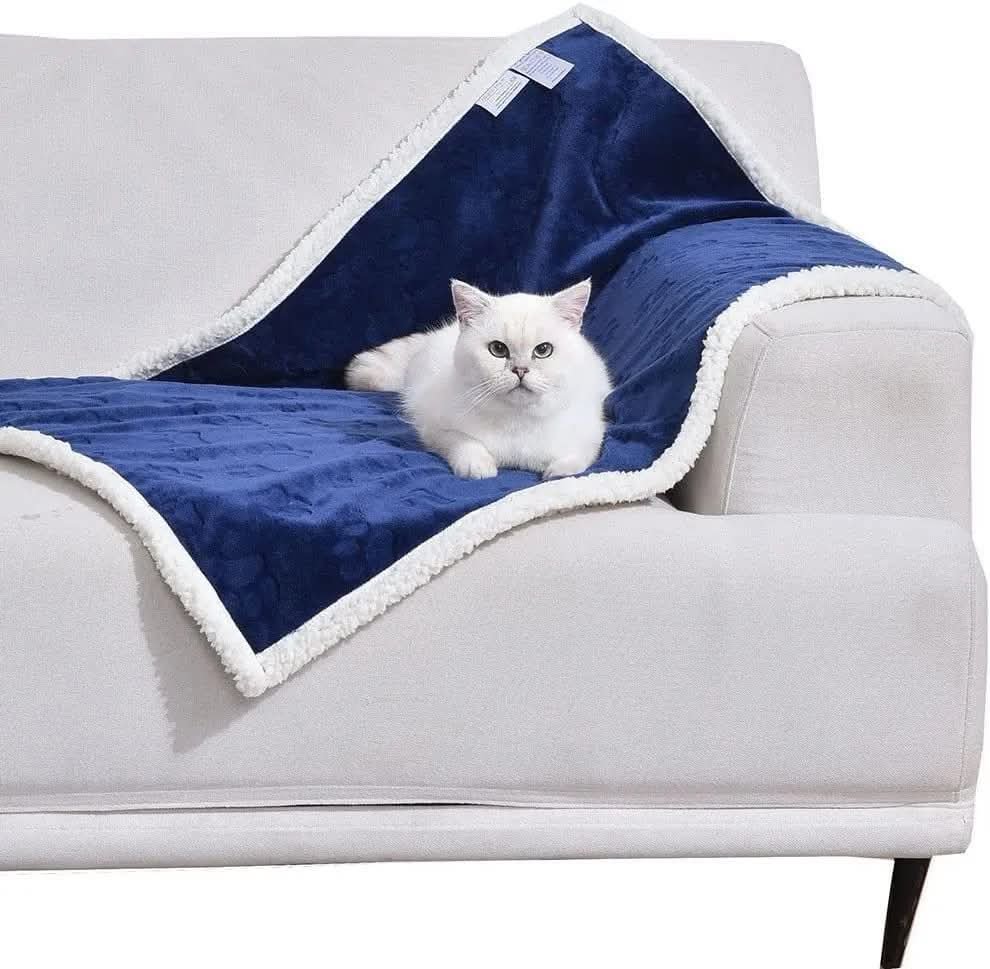 Waterproof reversible dog blanket in navy blue draped on a sofa