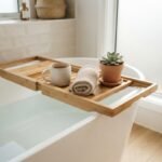 A wooden best bath caddy australia set across a white bathtub with a mug and towel in a bright bathroom