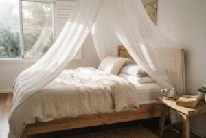 A dreamy sheer white bed canopy hanging over a cozy made bed in a sunlit Australian bedroom.