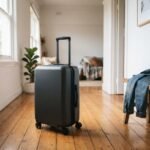 A sleek unbranded carry-on suitcase standing in a brightly lit Australian home hallway.