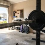A steel barbell loaded with bumper plates in a sunlit home gym, representing the best olympic barbell in Australia.