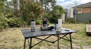 A top-rated camping table for sale in Australia, shown in a realistic outdoor setting.